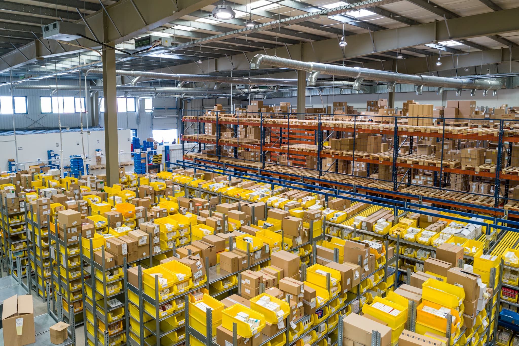 Warehouse aisles with workers and stacked pallets
